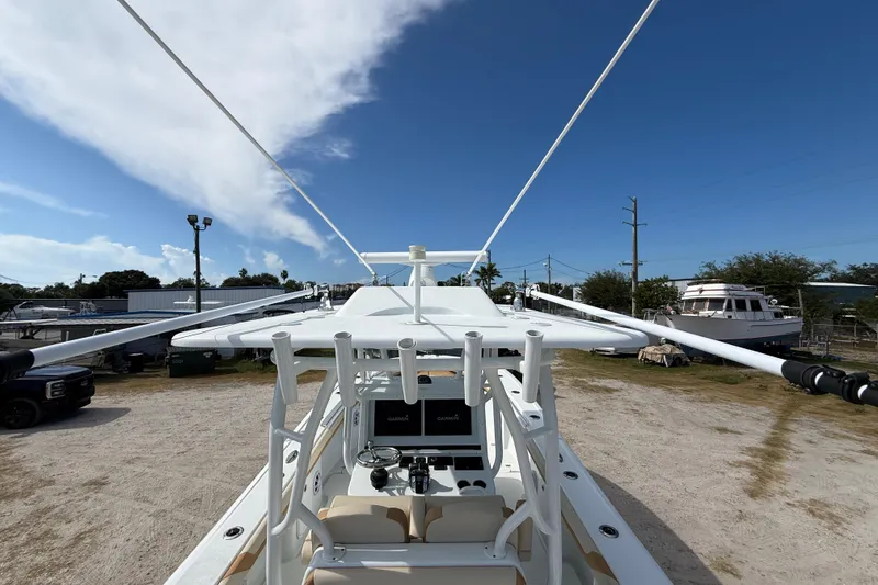 Slide: The Image of 2018 Yellowfin 32 Offshore boat with outriggers, parked outdoors under a clear blue sky. - 33