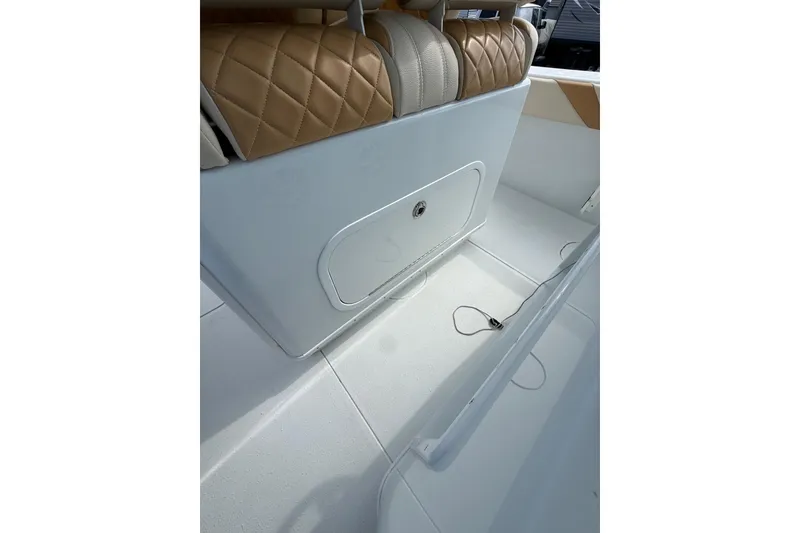 Slide: The Image of 2018 Yellowfin 32 Offshore boat interior with tan quilted seating and storage compartment. - 47