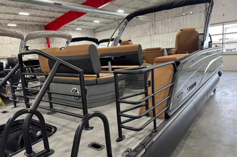 Slide: The Image of 2026 Sylvan L5 DLZ Platinum pontoon boat with tan seating in a showroom. - 6
