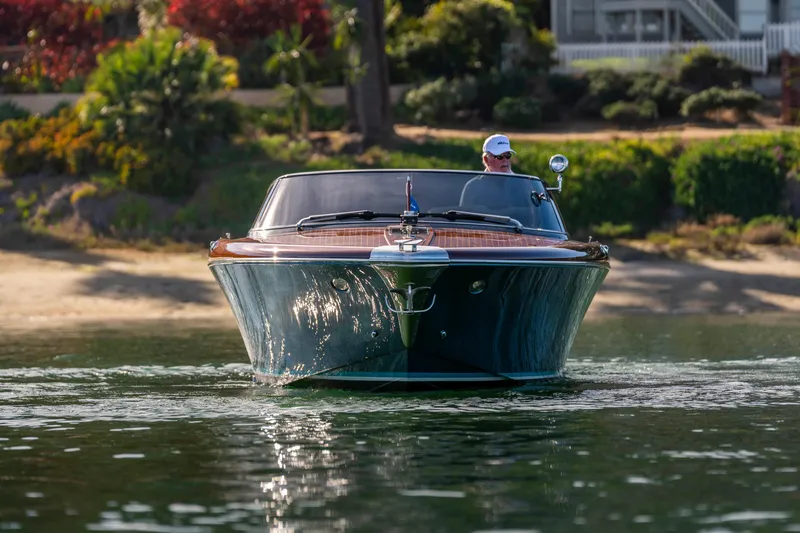 Slide: The Image of 2026 Riva 33' Aquariva Special cruising on calm water, surrounded by lush greenery. - 11