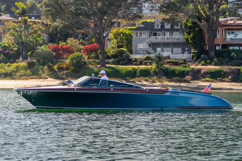 Slide: The Image of 2026 Riva 33' Aquariva Special cruising on a scenic lake with lush greenery. - 8