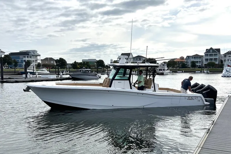 Slide: The Image of 2023 Caymas 341 CC boat docked in a serene marina setting. - 2