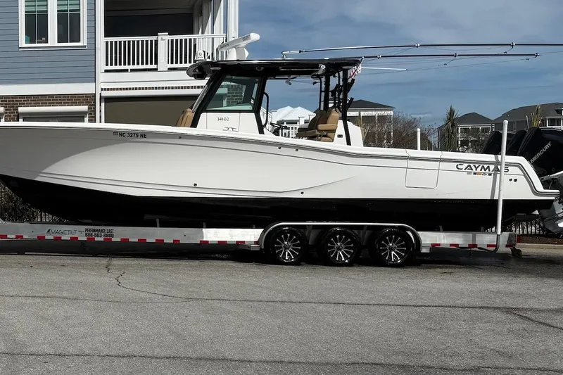Slide: The Image of 2023 Caymas 341 CC boat on trailer, parked near residential buildings. - 24
