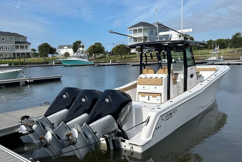 Slide: The Image of 2023 Caymas 341 CC boat docked with triple outboard engines in a marina setting. - 4