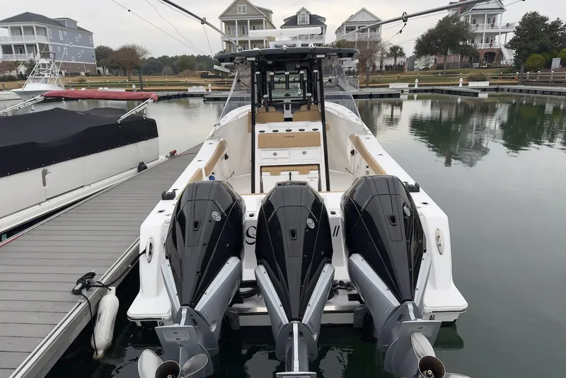 Slide: The Image of 2023 Caymas 341 CC boat docked with triple outboard engines, marina background. - 5