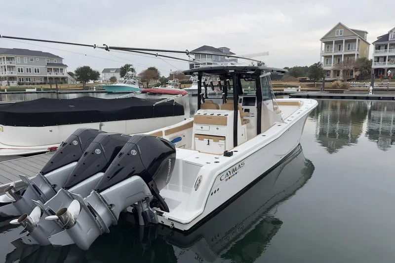 Slide: The Image of 2023 Caymas 341 CC boat docked in a marina with triple outboard engines. - 6