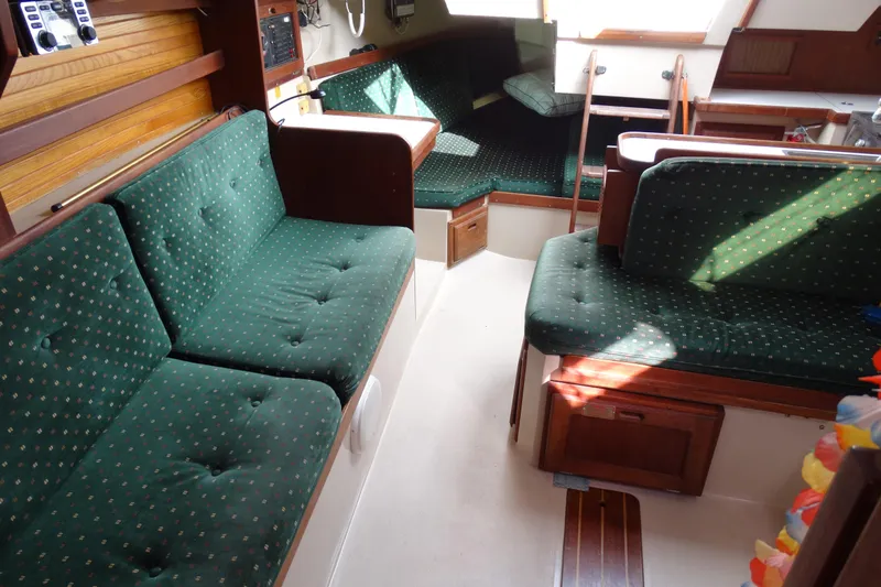 Slide: The Image of Interior of 1988 Catalina MKII sailboat with green cushioned seating and wooden accents. - 13