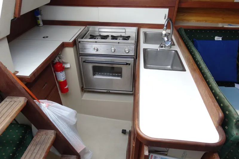 Slide: The Image of Compact kitchen in a 1988 Catalina MKll sailboat with stove, sink, and fire extinguisher. - 19