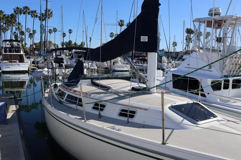 Slide: The Image of 1988 Catalina 30 MkII sailboat docked in a marina with palm trees in the background. - 2