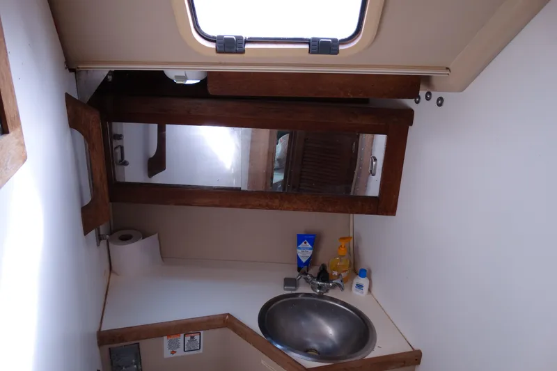 Slide: The Image of 1988 Catalina MKII boat bathroom with sink, mirror, and toiletries. - 21
