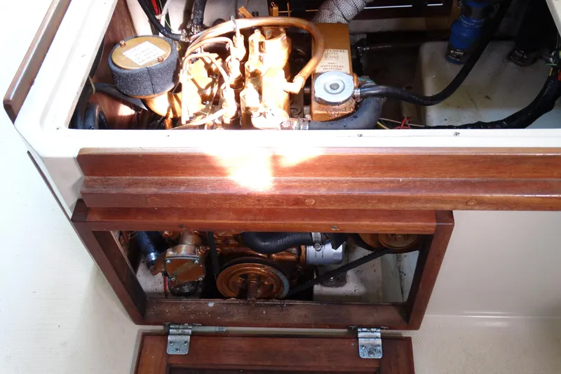 Slide: The Image of Engine compartment of a 1988 Catalina MKII sailboat, showcasing mechanical components and wooden paneling. - 35