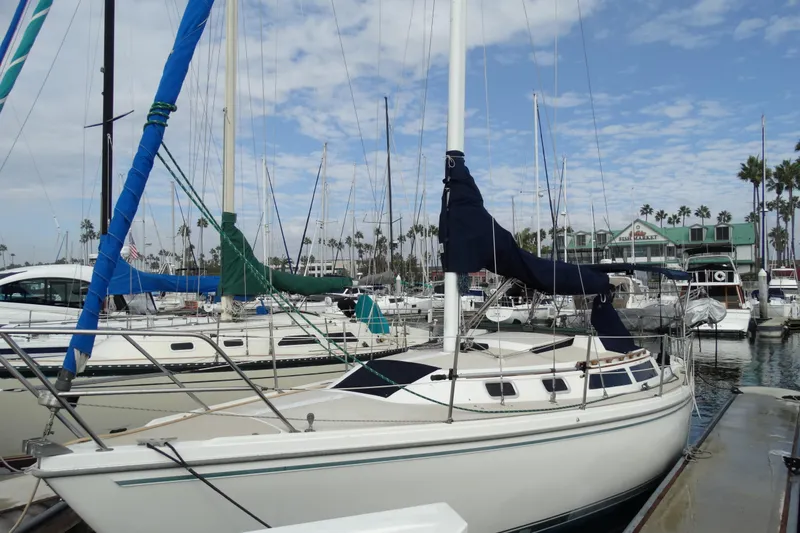 Slide: The Image of 1988 Catalina MKll sailboat docked at a marina under a partly cloudy sky. - 7