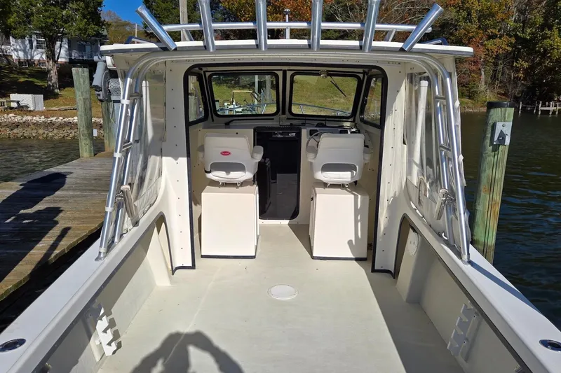 Slide: The Image of 2015 May-Craft 2550 Pilot XL boat interior at dock, featuring helm and seating. - 17