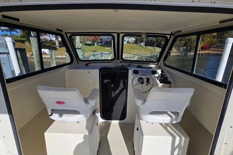 Slide: The Image of Interior of 2015 May-Craft 2550 Pilot XL boat with dual white seats and steering console. - 22