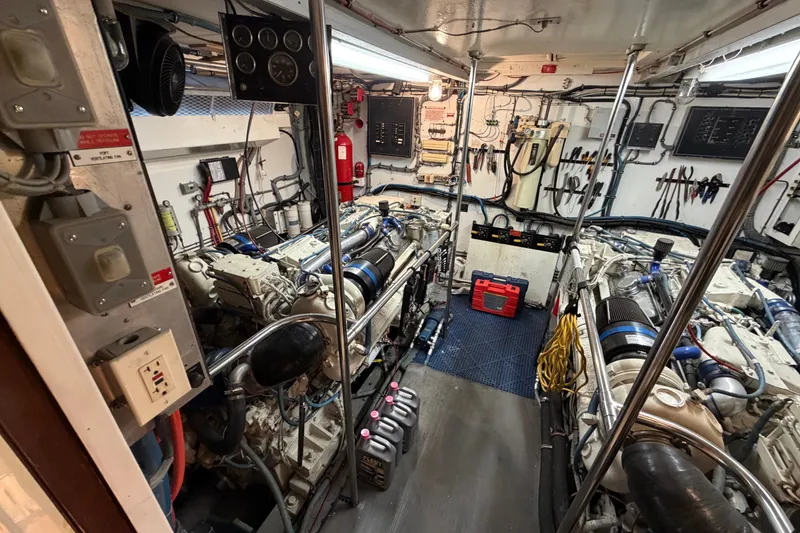 Slide: The Image of Engine room of a 1991 Hatteras 70 Motor Yacht, featuring dual engines and maintenance tools. - 110