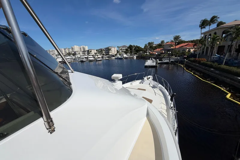 Slide: The Image of 1991 Hatteras 70 Motor Yacht docked in a sunny marina with waterfront homes. - 13