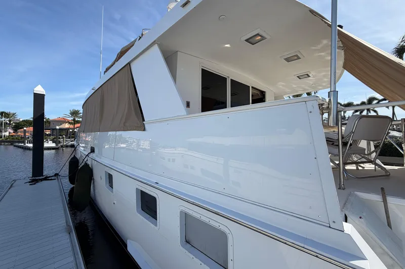 Slide: The Image of 1991 Hatteras 70 Motor Yacht docked, showcasing sleek design and spacious deck area. - 18