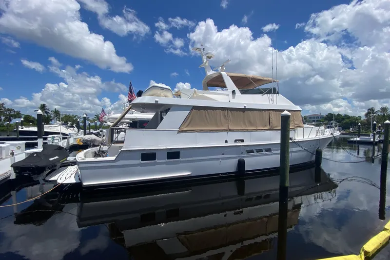 Slide: The Image of 1991 Hatteras 70 Motor Yacht docked under a bright blue sky with clouds. - 2