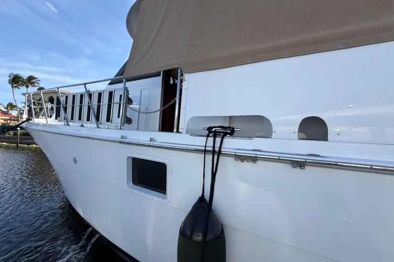Slide: The Image of 1991 Hatteras 70 Motor Yacht docked, featuring sleek white exterior and protective fender. - 22