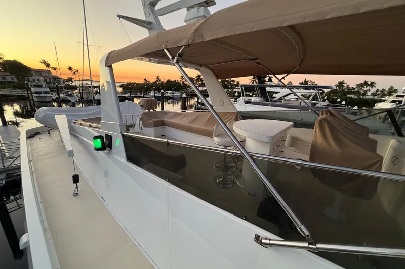 Slide: The Image of 1991 Hatteras 70 Motor Yacht docked at sunset, featuring covered seating and sleek design. - 27
