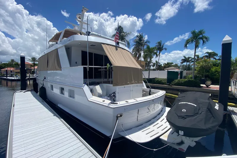 Slide: The Image of 1991 Hatteras 70 Motor Yacht docked under a sunny sky with palm trees. - 3