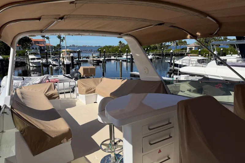 Slide: The Image of 1991 Hatteras 70 Motor Yacht interior with covered seating, docked at a marina. - 40