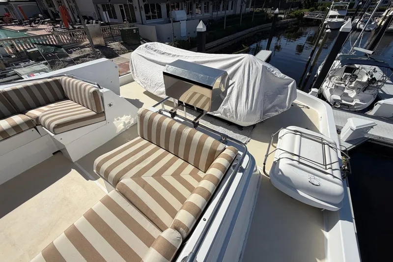 Slide: The Image of 1991 Hatteras 70 Motor Yacht deck with striped seating and covered equipment. - 51