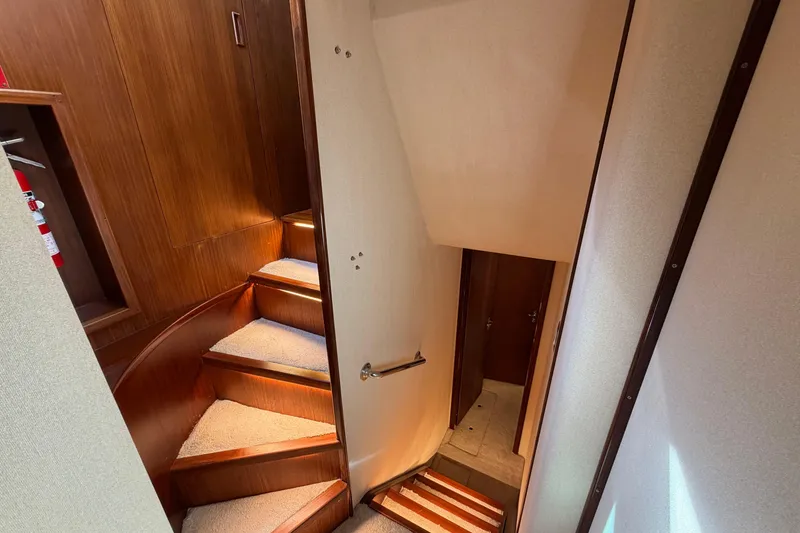 Slide: The Image of Staircase inside 1991 Hatteras 70 Motor Yacht with wooden paneling and carpeted steps. - 75