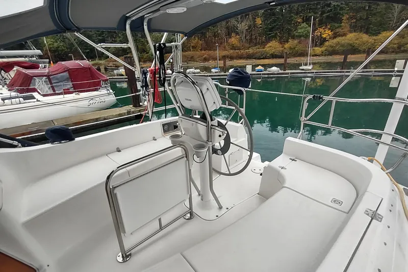 Slide: The Image of 2003 Hunter 356 sailboat cockpit with steering wheel, docked in a serene marina setting. - 18
