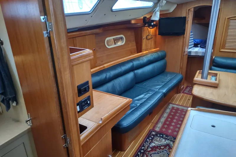 Slide: The Image of Interior of a 2003 Hunter 356 sailboat with wood finish and blue seating. - 28
