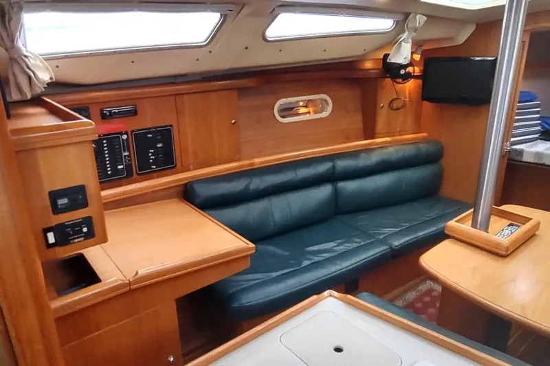 Slide: The Image of Interior of a 2003 Hunter 356 sailboat with wood finish and green leather seating. - 29