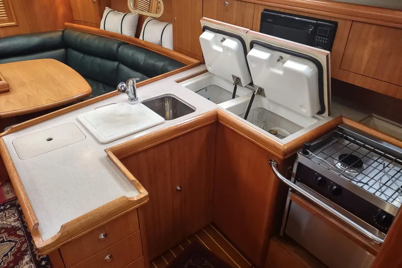 Slide: The Image of 2003 Hunter 356 yacht interior with kitchen, sink, stove, and seating area. - 31