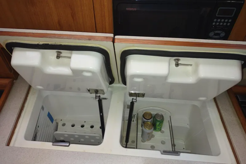 Slide: The Image of Open storage compartments in a 2003 Hunter 356 yacht galley with canned beverages inside. - 32