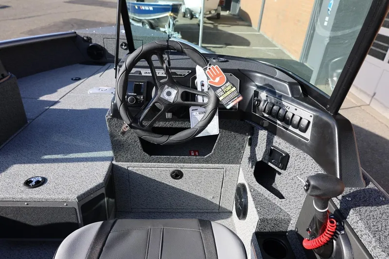 Slide: The Image of 2026 Lund 1875 Impact XS Sport boat interior with steering wheel and control panel. - 16