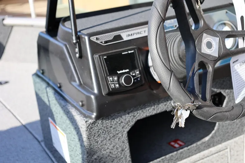 Slide: The Image of 2026 Lund 1875 Impact XS Sport boat dashboard with steering wheel and keys. - 18