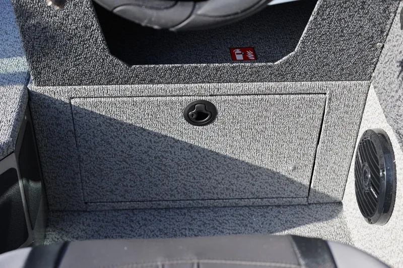Slide: The Image of Interior of 2026 Lund 1875 Impact XS Sport boat, featuring storage compartment and speaker. - 19