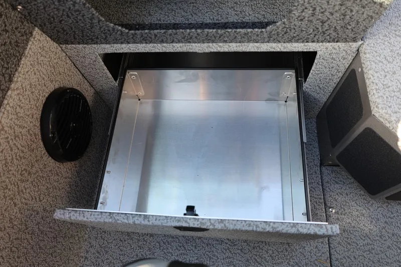 Slide: The Image of 2026 Lund 1875 Impact XS Sport boat storage compartment with carpeted interior and speaker. - 25