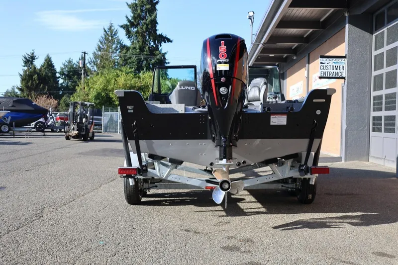Slide: The Image of 2026 Lund 1875 Impact XS Sport boat with powerful outboard motor, parked outdoors. - 44