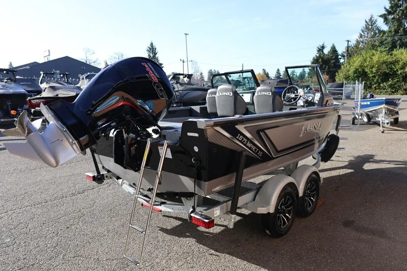 Slide: The Image of 2026 Lund 1875 Impact XS Sport boat with powerful outboard motor, parked on a trailer. - 5