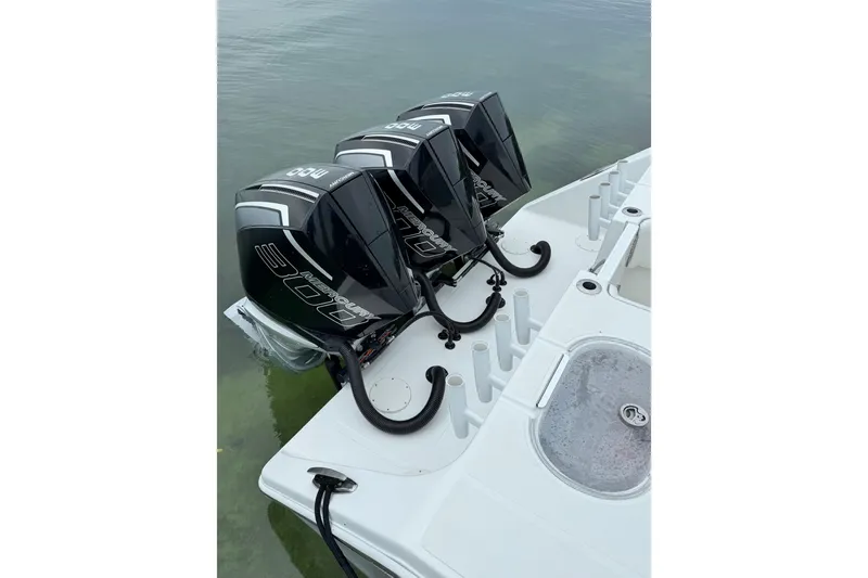 Slide: The Image of Triple outboard motors on a 2022 SeaHunter 33 Tournament boat, docked on calm water. - 10