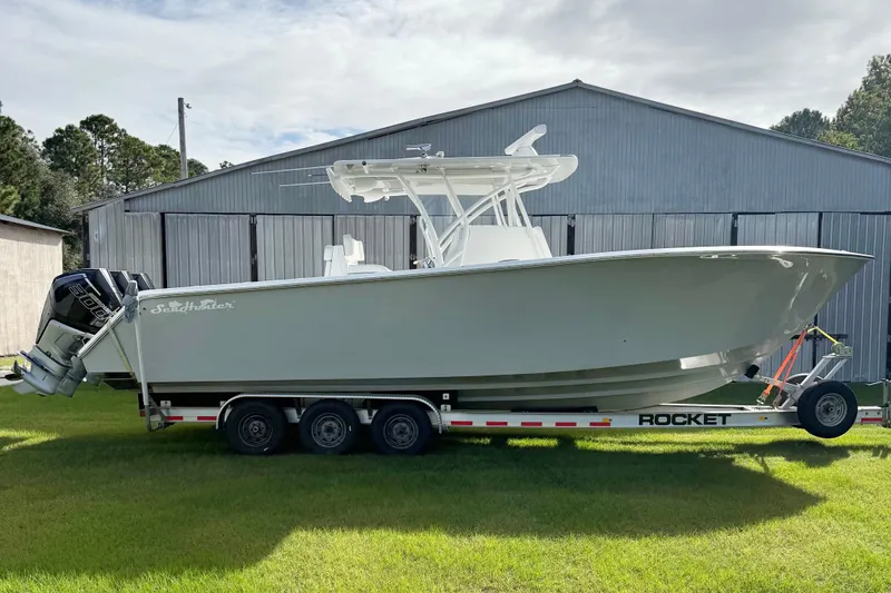 Slide: The Image of 2022 SeaHunter 33 Tournament boat on a trailer, parked on grass. - 6