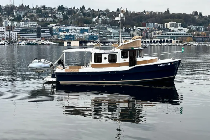 The Image of 2017 Ranger Tugs R-31 CB boat on calm water with cityscape background. - 0