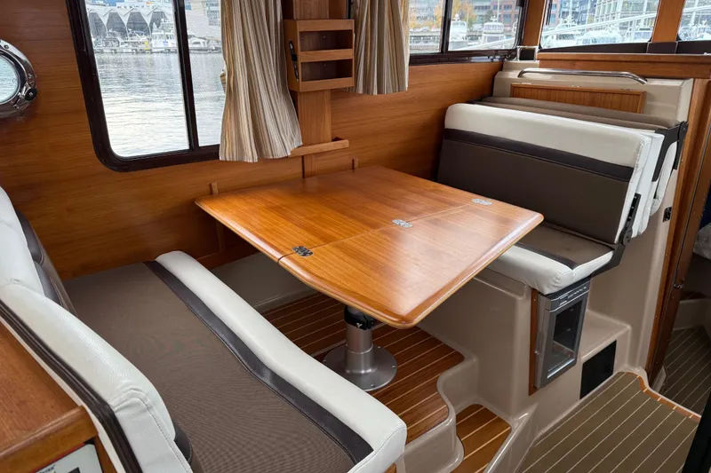 Slide: The Image of Interior of 2017 Ranger Tugs R-31 CB with wooden table and cushioned seating. - 21