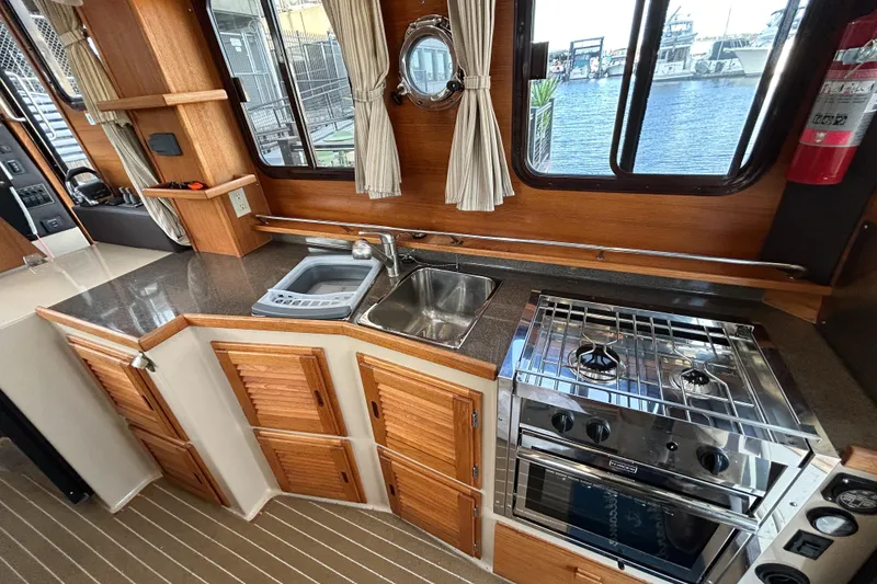 Slide: The Image of 2017 Ranger Tugs R-31 CB interior kitchen with stove, sink, and wooden cabinetry. - 27
