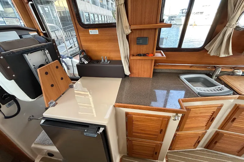 Slide: The Image of 2017 Ranger Tugs R-31 CB interior kitchen with wood cabinetry and compact appliances. - 28