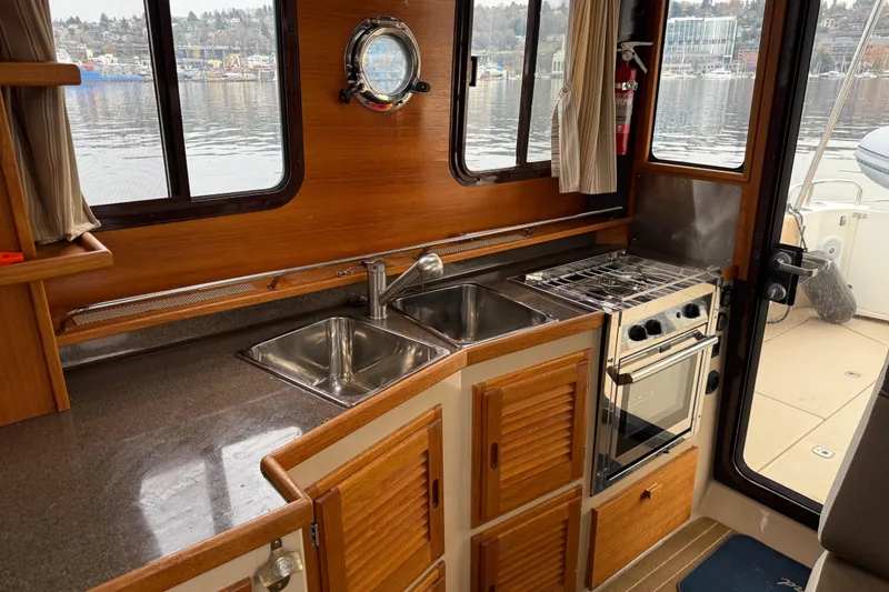 Slide: The Image of 2017 Ranger Tugs R-31 CB interior kitchen with sink, stove, and wooden cabinetry. - 30