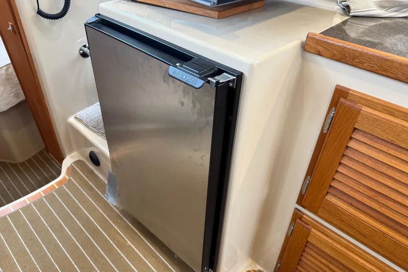 Slide: The Image of 2017 Ranger Tugs R-31 CB interior with stainless steel fridge and wooden cabinetry. - 35