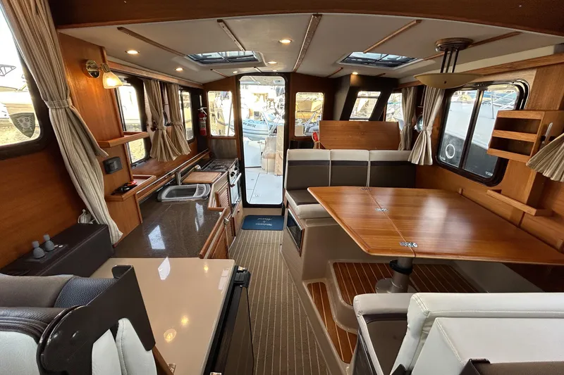 Slide: The Image of 2017 Ranger Tugs R-31 CB interior with wood finishes and spacious seating area. - 5