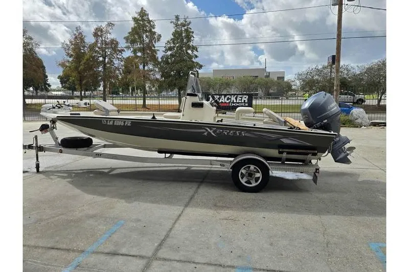 Slide: The Image of 2012 Xpress H20 boat on trailer, parked outdoors under cloudy sky. - 6