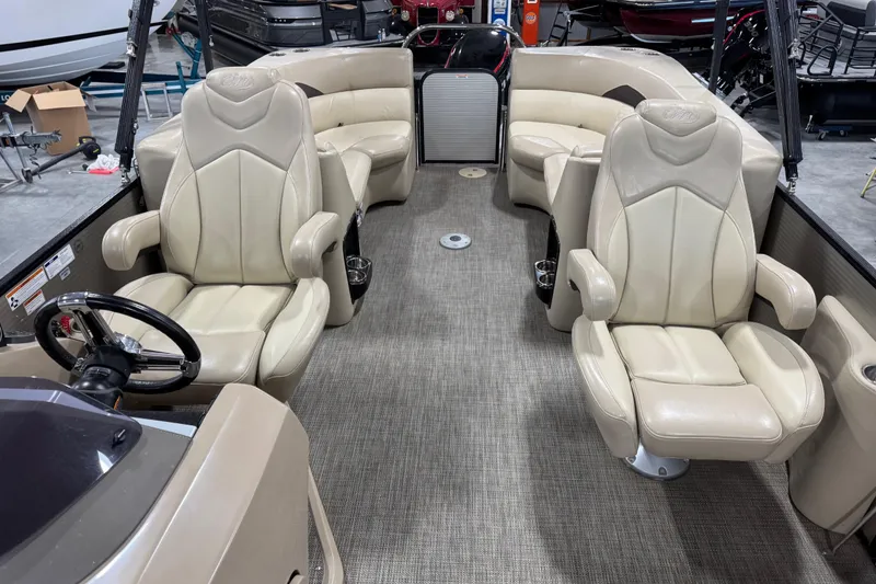 Slide: The Image of 2019 Manitou 250 Encore SHP boat interior with beige leather seating and steering wheel. - 10